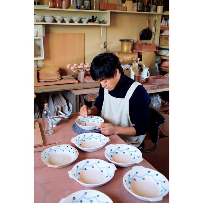 〈ミナ ペルホネン〉の皆川 明と陶作家の安藤雅信による陶作展は今年で4回目。岐阜県多治見市にある安藤の工房で、”雪の器”をテーマに絵付けする皆川。