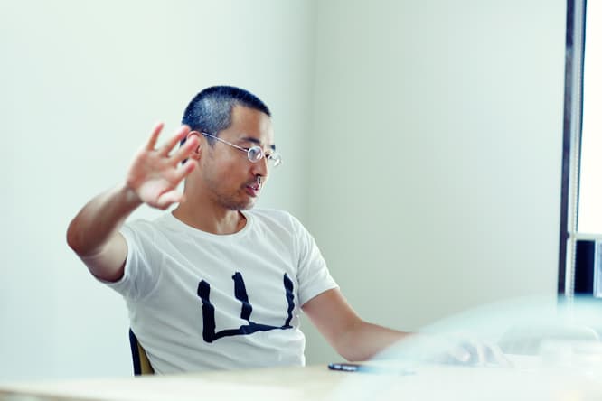 身ぶり、手ぶりをまじえながら仕事について語る代表の小板橋さん。〈アカオニデザイン〉の多くの仕事はプレイングマネージャーである彼の手を経由する。