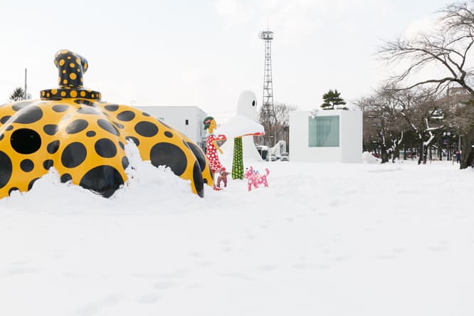 草間彌生《愛はとこしえ十和田でうたう》。かぼちゃ、犬、きのこ、少女など8つの彫刻からなる大規模な作品は、アート広場の中央に。右奥はインゲス・イデー（ドイツ）の《ゴースト》と《アンノウン・マス》。後者は西沢立衛設計の公衆トイレを覗き込んでいる。