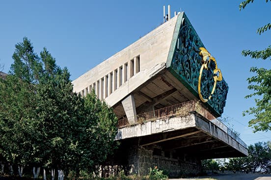 1976年竣工。丘の上に建つ産業大学の大講義室。正面についた、金の羽を広げたブロンズ製のバットマン（？）の社会主義的なレリーフが面白い。現在も大学の一部だが、使われておらず老朽化が進む。