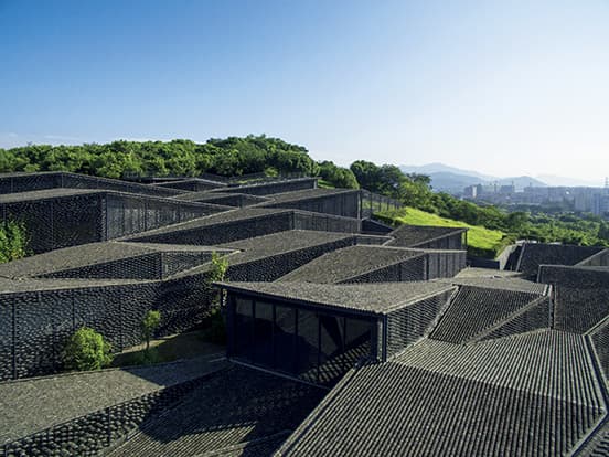 小高い丘の中腹に建つミュージアム。屋根や壁の古い瓦が風景に溶け込む。建物の大きさは約5,000㎡、展示室は7つある。