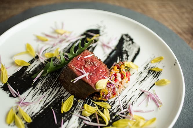 「あか牛 長葱 菊」。真っ黒なソースは長ネギを丸ごと焼いた周りの焦げ。トロトロになるまで火を入れた長ネギの甘みと焦げの苦みが、イチボの旨みとマッチ。