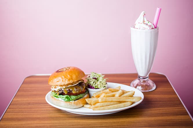 「エッグチーズバーガー」1,300円と「クランベリー ミルクシェイク」630円。具の味わいを際立たせるため、あえてバンズは東京・平井〈サンワローラン〉のラインアップのなかでも旨みが控えめのものをチョイス。サクッとした歯切れのよさにもこだわった。