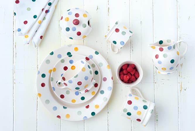 食器の絵柄はスポンジの先端に型を彫刻して絵の具をつけモチーフの一つ一つを型押しして製作。左上から時計回りに／《Polka Dot》シリーズのナプキン1,100円、シュガーポット3,600円、スモールマグ参考商品、ジャグ3,200円、ラムカン（3個セット）4,500円、マグ3,500円、プレート（26.8cm）2,800円、ティーカップ＆ソーサー4,100円。