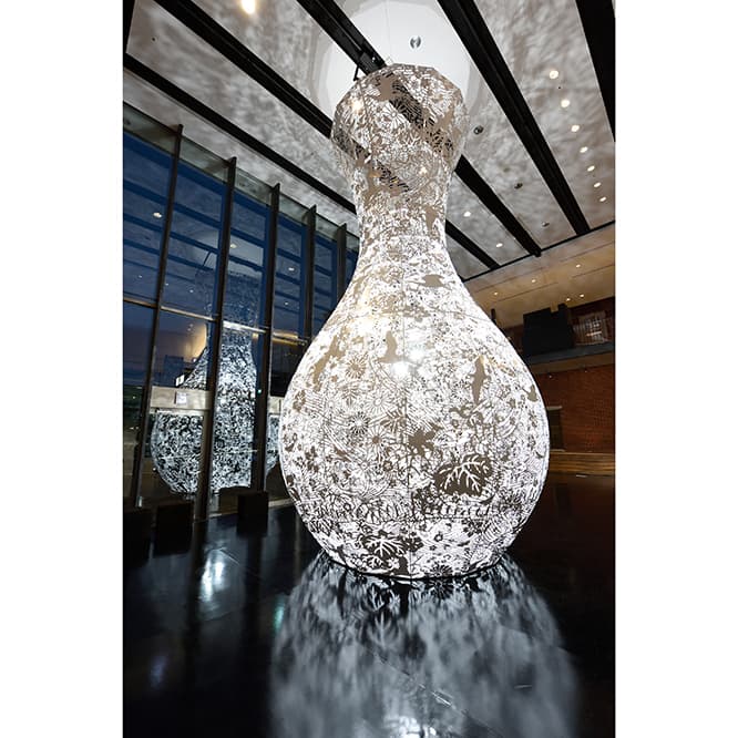 《重力と恩寵》（2016年）。「あいちトリエンナーレ」穂の国とよはし芸術劇場PLATでの展示。透かし彫りが施されたオブジェの中を、強烈な光源が上下する。 photo_Ito Tetsuo　2016 Aichi Triennale Organizing Committee