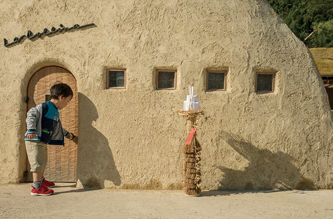 写真撮影のためのモニュメント〈土塔〉。モルタル仕上げで、輪郭に沿って五葉松が植えられている。小さなドアが、子供たちの格好の遊び場に。