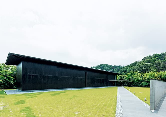 黒い杉板が森に映える美術館〈森の中の家 安野光雅館〉。