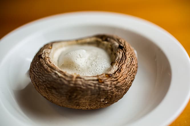 料理はすべて《ケジャン★オールスターズおまかせコース》8,500円より。1品めはトリュフ塩で風味付けした《トリュフ風味のマッシュルーム》。大きめのマッシュルームは網で焼くと、かさの内側にしみ出してくるうまみエキスがスープ代わり。