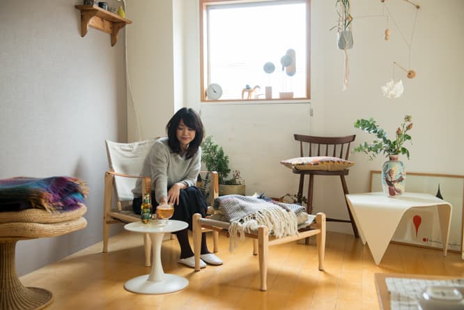 こにしあきこ　〈イッタラ〉や〈アラビア〉〈レ・クリント〉などを扱う〈スキャンデックス〉のクリエイティブディレクター。知られざるノルウェーのデザインを発信する〈ノルウェージャンアイコンズ〉のPRやアドバイザーも兼任。20代より住宅、飲食プロデュース会社やミッドセンチュリー家具ショップ、北欧インテリアブランドで経験を積み、バイヤーやディレクターとして活躍。写真はコーア・クリントの《KK47000》サファリチェア＆オットマンやお気に入りの家具に囲まれた自宅でくつろぐ小西さん。