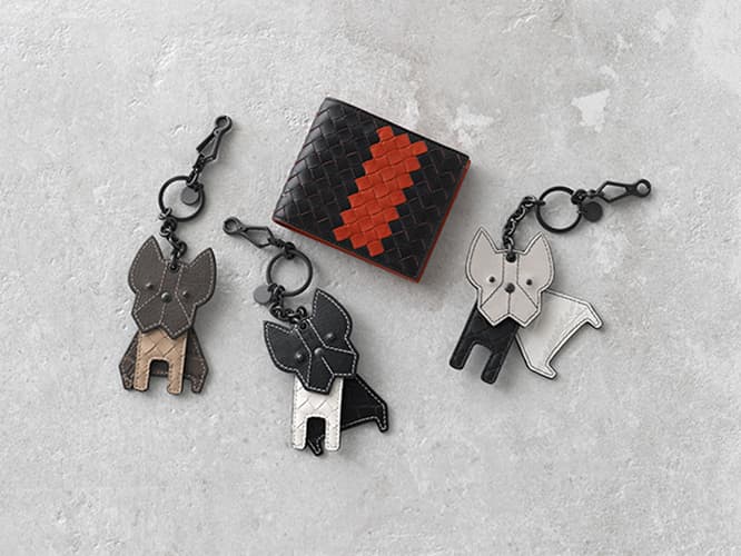 〈BOTTEGA VENETA〉ギフトの定番、小物の贈り物は“革”がいい。アイコニックなイントレチャートをあしらった財布は手に取るだけで、レザーの上質さが伝わってくる。さらにシンプルなブラックに鮮やかな赤のコントラスがアクセントに。3種類の革を贅沢に使ったフレンチブルドッグのキーリングをバッグに付ければ、ゆらゆら揺れて、一緒にお散歩気分。お財布 55,000円。キーリング 各65,000円。（ボッテガ・ヴェネタ／ボッテガ・ヴェネタ ジャパン TEL 0120 60 1966）

