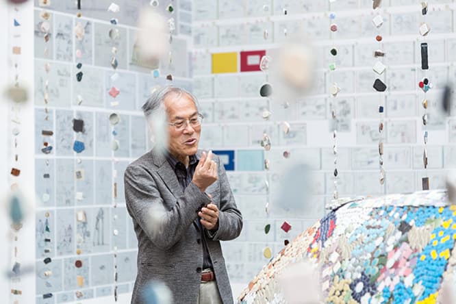 展示室での藤森照信。周りに下がっているすだれのようなものは、彼が設計した〈多治見市モザイクタイルミュージアム〉で展示されているモザイクタイルで作ったもの。