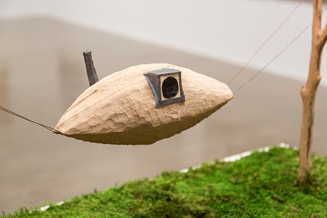 空中に吊された〈空飛ぶ泥舟〉の模型。実際ははしごをかけて上り下りする。この個展に展示されている藤森の卒業制作も細長いUFOのような構造物を谷間に掛け渡すつくりだ。