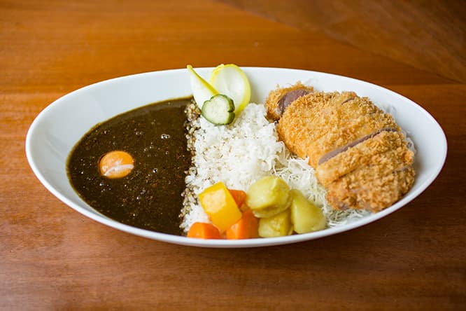 スリランカのローストカレー粉を使った「カツカレー（ロース）」1,300円に「ギョクオチ（卵黄）」80円をプラス（以下、税込）。玉ネギとキュウリのピクルス、ニンジンとジャガイモのサブジ（インド風炒め煮）添え。
