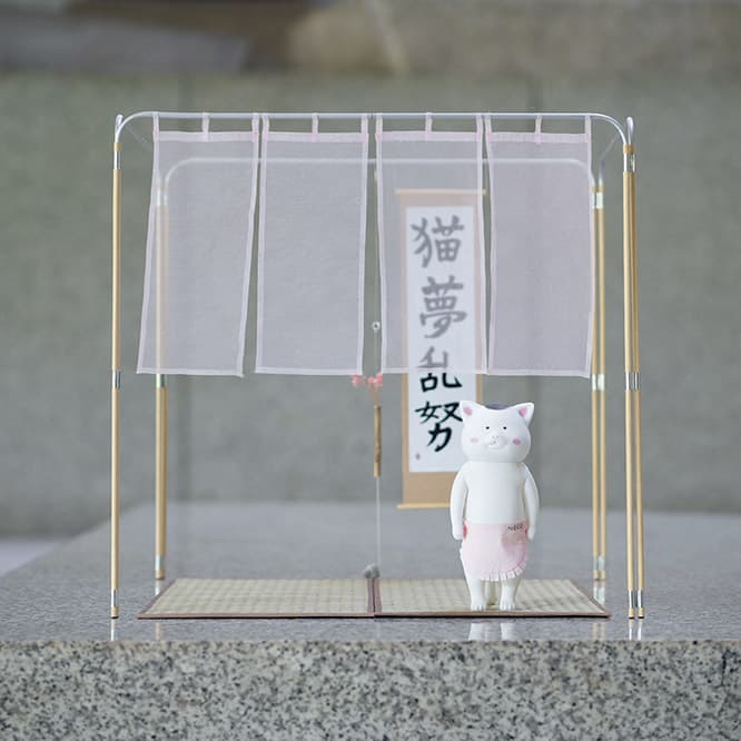 Jo Nagasaka【茶室】　組立式で、分解すればどこへでも運べるモバイル茶室。考案したのは〈スキーマ建築計画〉の長坂常だ。ビニールハウス用のパイプと紙管を組み立てて自立させ、床に2畳分の琉球ゴザを敷くスケルトンスタイル。手前には蚊帳生地の御簾（みす）を垂らして躙（にじ）り口とした。運搬用の特注三輪車のほか、4分の1サイズの模型（写真）も展示。