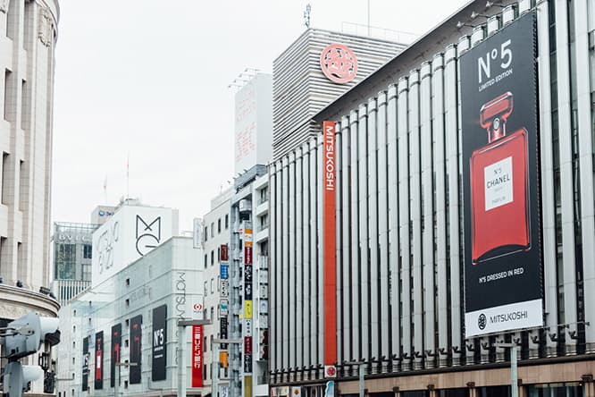 手前に〈銀座三越〉、奥に〈松屋銀座〉と、銀座の目抜き通りを《シャネル N°5》が埋め尽くしている。©CHANEL 
