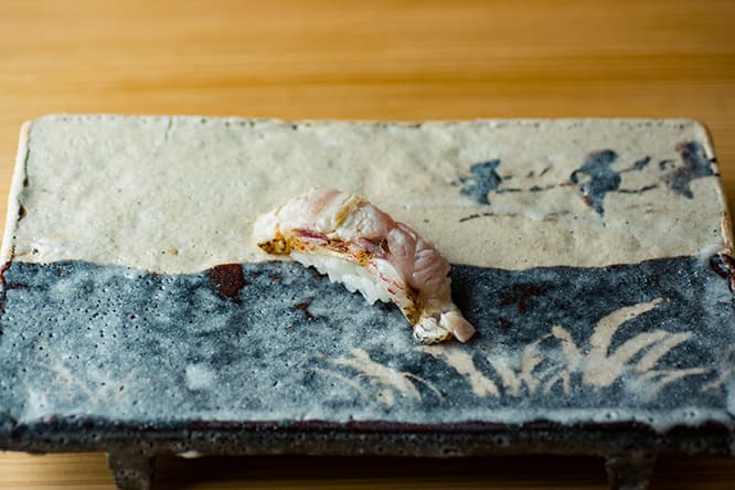 脂がのったのどぐろの皮目を炙って、焼き霜造りにし、握りに仕上げた「のどぐろの炙り」。商品として店で出したのは寿司史上、光川が初めて。実力派作家、瀧川恵美子のまな板皿で。