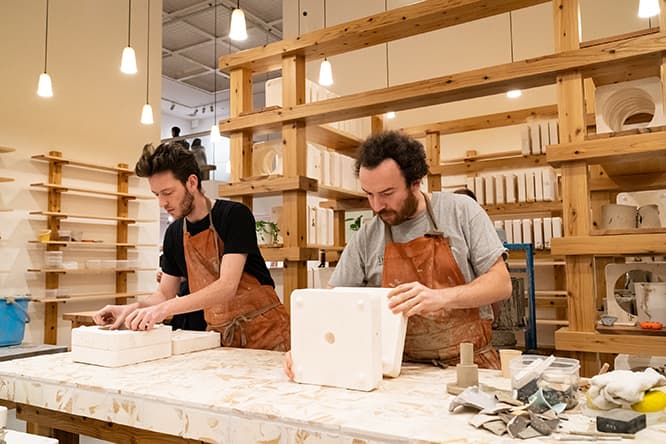 本展のため〈アッセンブル〉と〈グランビーワークショップ〉のチームが来日してワークショップから窯焼き、完成品展示までを手がけた。写真はスタッフのアダム（左）とルイス。photo_Ken Kato