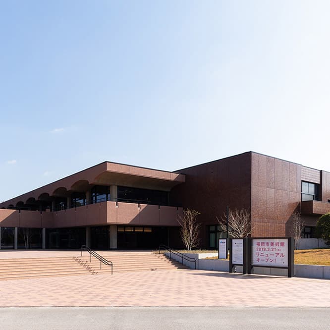 大濠公園の池に面する、美術館の西側にエントランスを新設。入り口近くのカフェからは、大濠公園の池を一望できる。〈東京都美術館〉でも用いられている「打ち込みタイル」工法による外壁が目を引く。photo_Shintaro Yamanaka（Qsyum!）