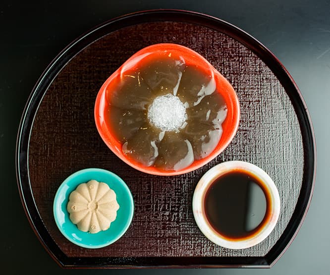 中央に氷をあしらい、お花のように並んだ「生わらびもち」1,080円。焙煎の深さが異なる大豆をブレンドしたきな粉、自家製黒蜜添え。