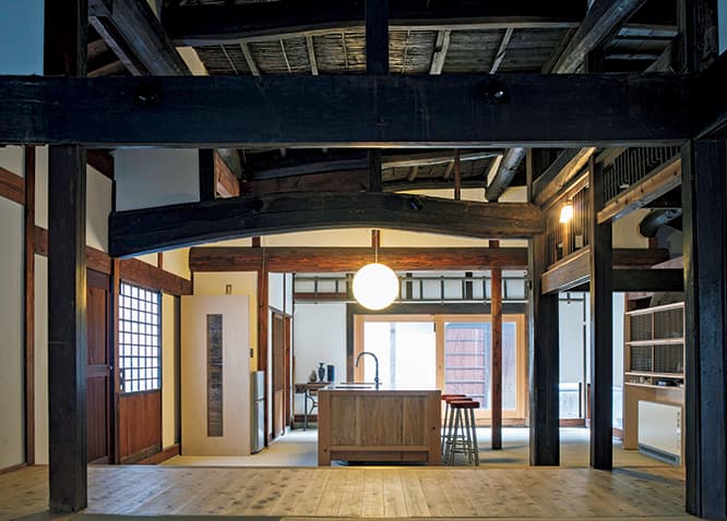 座敷からキッチンを見る。内装は既存の建物に合わせ、ヒノキや漆喰で仕上げている。棚やキッチンに既存の建具や欄間を活用。