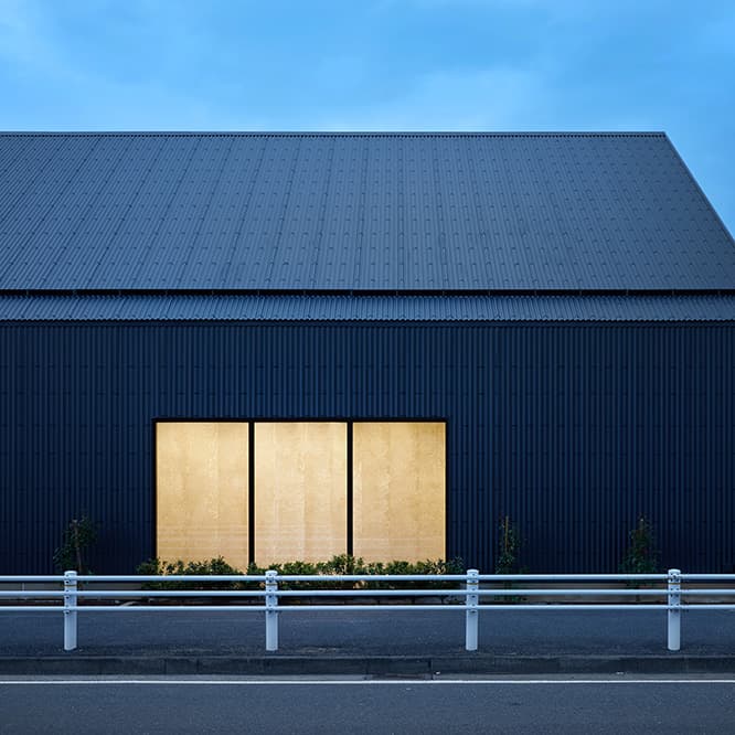 周囲の景観にも配慮された、まるで住宅のような落ち着いた雰囲気の工場に。珈琲豆を使った壁材は、開口部を通して外からも覗ける。