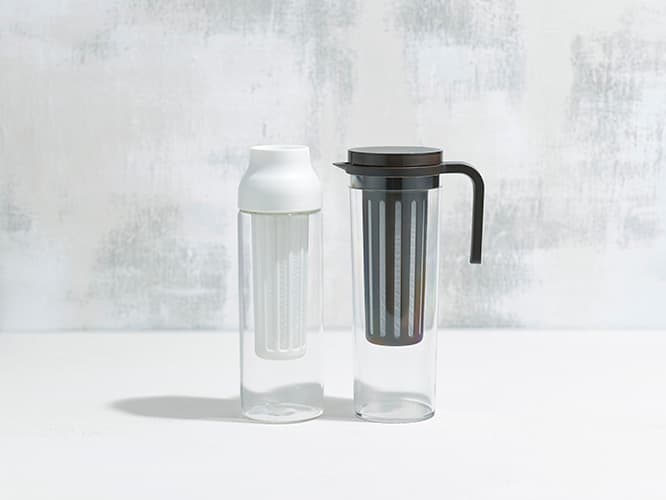 （左）KINTO《CAPSULE コールドブリューカラフェ ホワイト》他にダークブラウンがある。φ85 x H270 mm。2,500円。容量1000ml。（右）《PLUG アイスコーヒージャグ ブラウン》φ95 x H270 x W150 mm。2,300円。容量1200ml。TEL 0120 34 7830。
