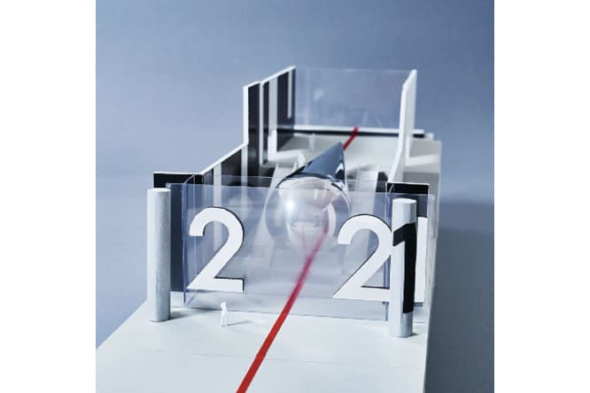 『2021#Tokyo Scope』の展示模型。青山通り側からビル正面を見ると2021の文字がガラス面に見える。2021の「0」はガラスの向こう側に据えられた鏡面のオブジェとなっており、通りに立つ鑑賞者や、東京の時間軸を表現した赤線が映り込む。オブジェの裏側へまわると複数のモニターがあり、これまで藤元が取り組んできた『2021#Tokyo Scope』のアーカイヴ映像などを見ることができる。