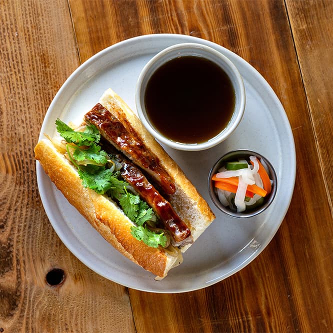 「牛バラのバインミー フレンチディップスタイル」1,200 円。フォーのスープにディップしながら食べる、新食感のバインミー。