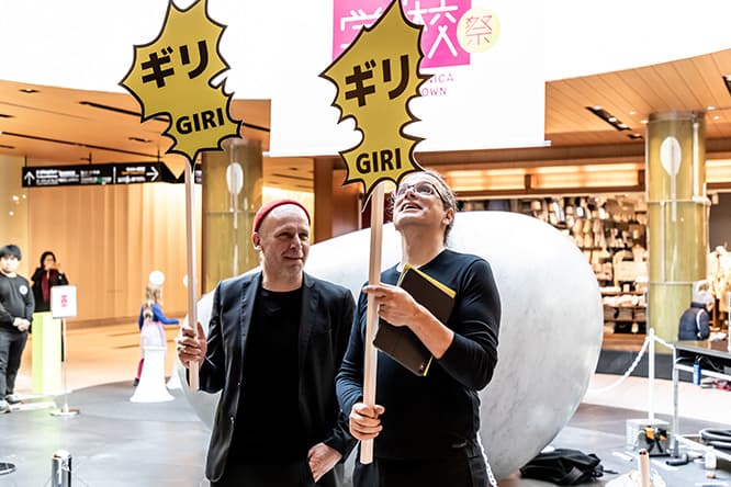 「ギリGIRI」と書かれた、漫画の吹き出しのようなプラカードを持つゲルフリート・シュトッカー（右）とマーティン・ホンツィック（左）。このプラカードは参加者が自由に持って撮影することができる。