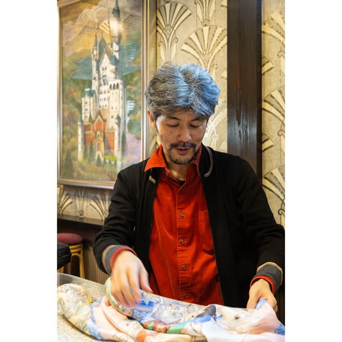 アトリエ近くにあるお馴染みの喫茶店で、出来上がったばかりのカレを見る山口。　photo_Manami Takahashi