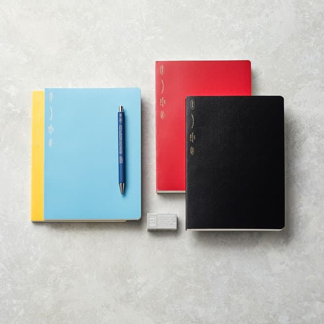 （左から）《1/2 イヤー ノート》（イエロー、ブルー）：A5サイズ（210x148mm）、192ページ、1,850円。〈シャープペンシル芯径 0.5mm〉（ブルー）660円。《365 デイズノート》（レッド、ブラック）：A5サイズ（210x148mm）、368ページ。2,550円。非塩化ビニール系の〈消しゴム〉154円。　ニトムズ お客様相談室 TEL  0570 05 2106。 