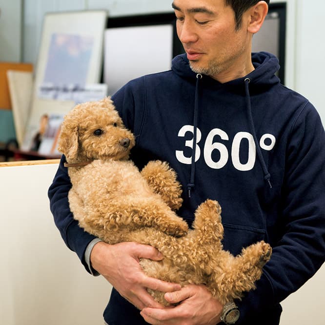 大好きな飼い主に抱っこされて、ご満悦のグー。昨年、納谷さんがアフロヘアだった時は、もじゃもじゃ具合が親子のようだったとか。