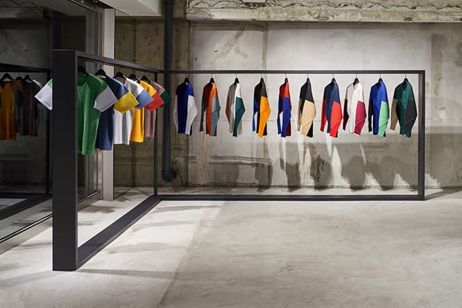 長袖丸首Tシャツ《COLORS》（14,000円）をはじめ、ショップ限定のアイテムが並ぶ一角。