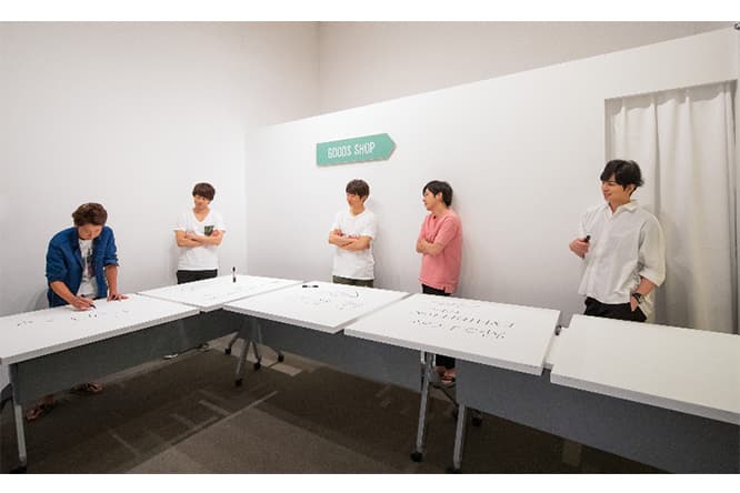 会場内でメッセージをボードに書く5人。