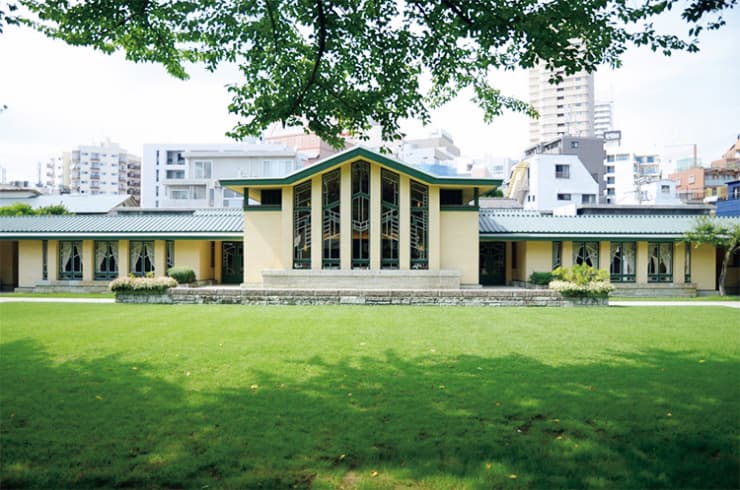 【自由学園明日館】1921年竣工。設計はフランク・ロイド・ライト。「高さをおさえて地に沿い広がる草原様式の建物。中央ホールの幾何学模様の窓、そのホールに置かれた六角形の背の椅子や壁画、食堂の照明など、かつてそこが女学校だったことを想像して眺めると感慨もひとしお」（甲斐みのり）