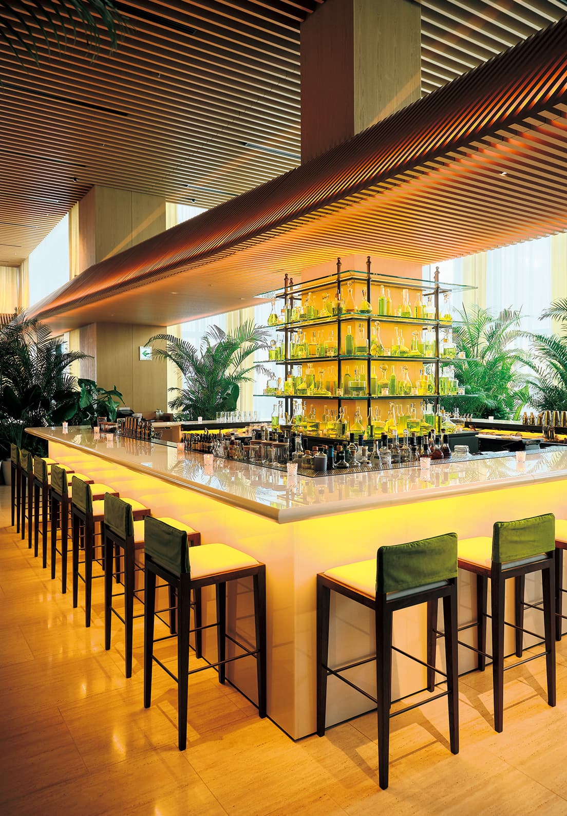 〈東京エディション虎ノ門〉の31階〈Lobby Bar〉。寺院の回廊を思わせる木製スラットの庇は隈研吾のデザイン。バーカウンターは白大理石、中央のシェルフは高透過ガラスといぶし加工のブロンズで作られている。photo_Masanori Kaneshita