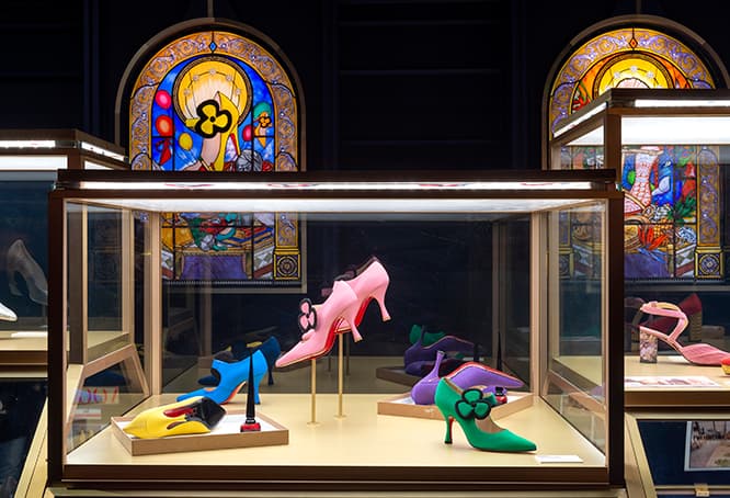全11の展示会場の一つ《初期》。スケッチを始めた高校時代や、家の屋根裏部屋で様々な形や素材の研究を重ねた頃の象徴として、ルブタンの守護聖人を表す特製のステンドグラスを配す。ブランド創設以前の初期のデザイン300足の中から、未発表の試作を含む約60点を当時のスケッチやムードボードとともに展示。© Marc Domage