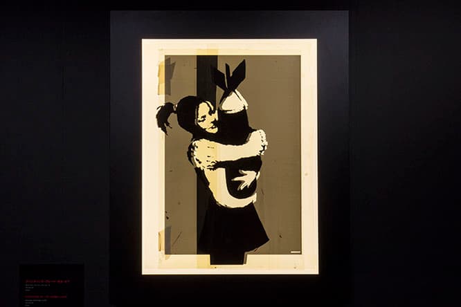 《PRINTING PLATE BOMB LOVE》（2003）爆弾を抱える少女を描いたステンシル作品《BOMB LOVE》の、貴重なオリジナルプレート。無邪気さと純粋さ、戦争の恐ろしさを象徴する作品。