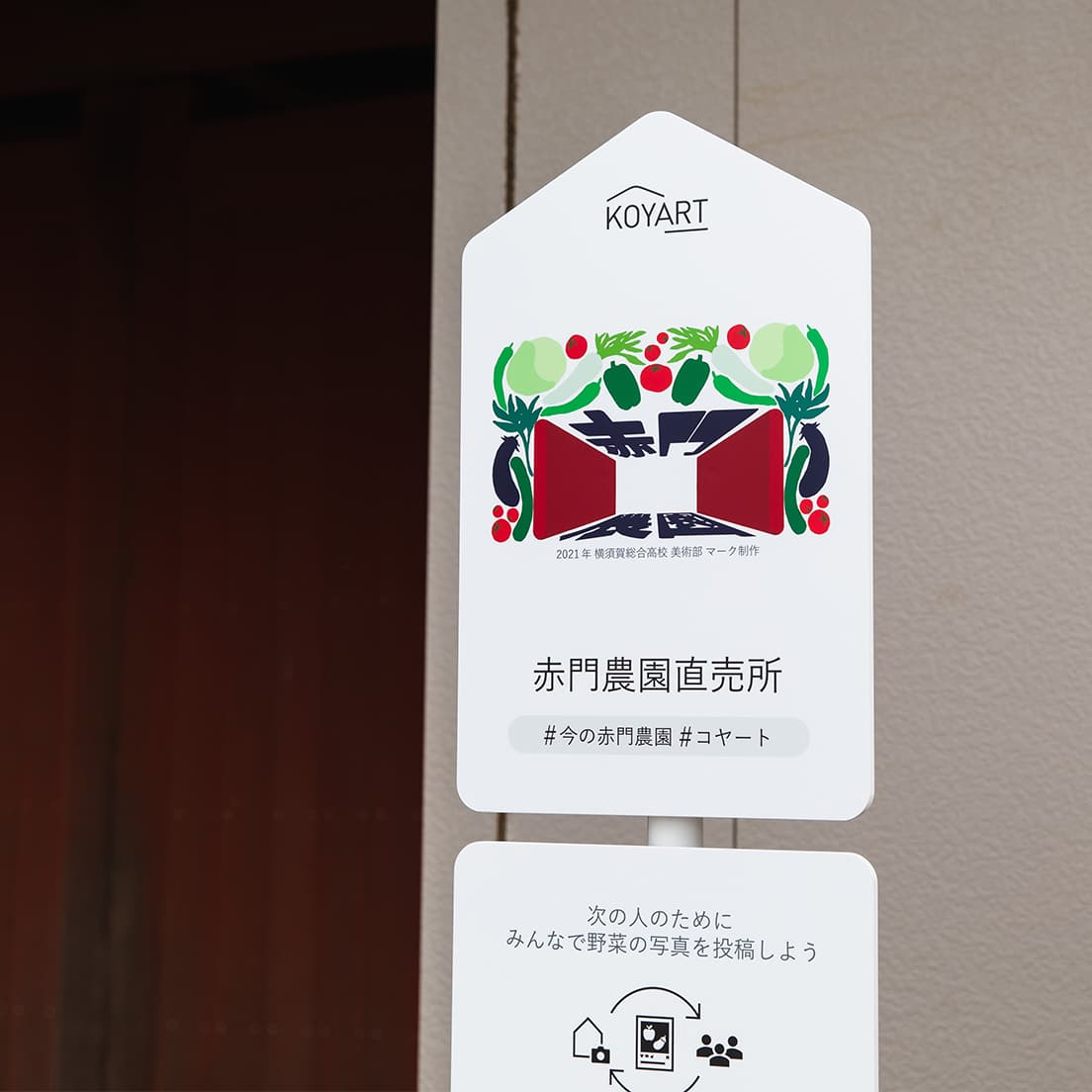 「赤門をブランドマークにしたい」という園主夫妻の要望に沿って、開かれた赤門と野菜がグラフィカルに組み合わさったマークが生まれた。デザイン：寺原ねね（横須賀市横須賀総合高等学校・2年生）