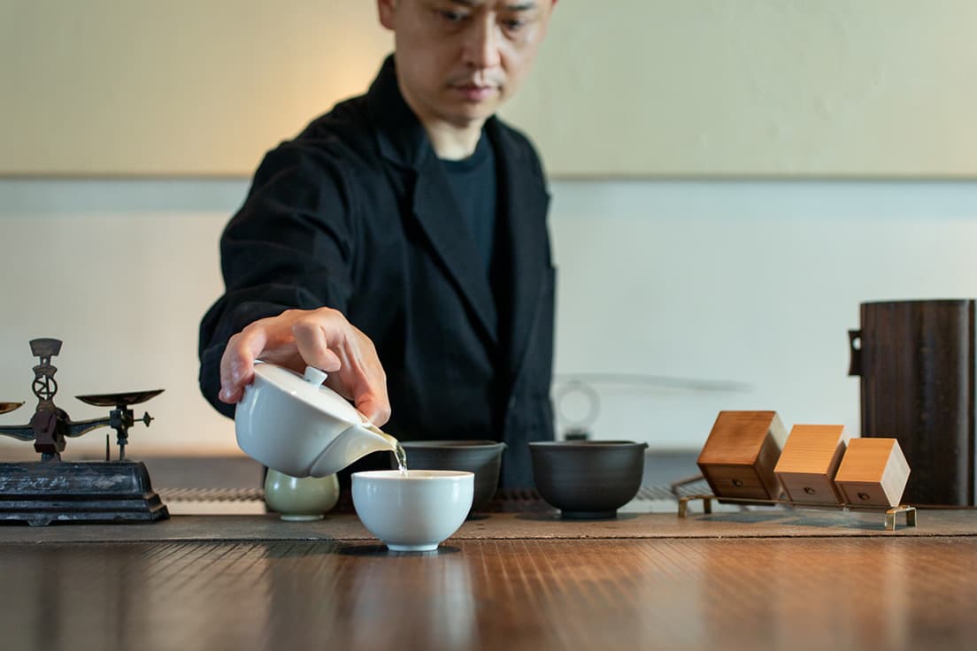 〈櫻井焙茶研究所〉代表でもある櫻井真也。〈茶方會〉が開発した白磁の丸湯呑は、持ちやすく口あたりのよい、丸みを帯びた形状。風合いのある白磁に鮮やかな茶の色合いが映える。