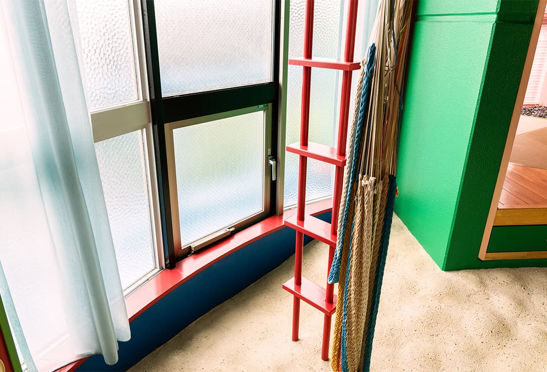 球状の部屋と畳部屋の中間に設置された、天井まで続く赤い梯子。まるで砂浜に埋まっているように見えます。近くには天井からロープで設置されたハンモックが備えられていて実際に使用も可能。窓面の中央下部はハンドル操作で開閉でき、茶室のにじり口のような感じで屋外のバルコニーへ出入りできるようになっています。