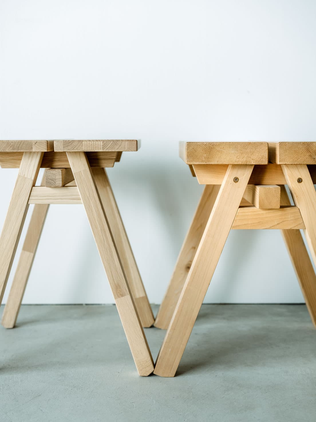 〈石巻工房〉の《ISHINOMAKI STOOL》（右）と、リデザインでスリムになった〈石巻工房 by Karimoku〉の《ISHINOMAKI STOOL by Karimoku》。