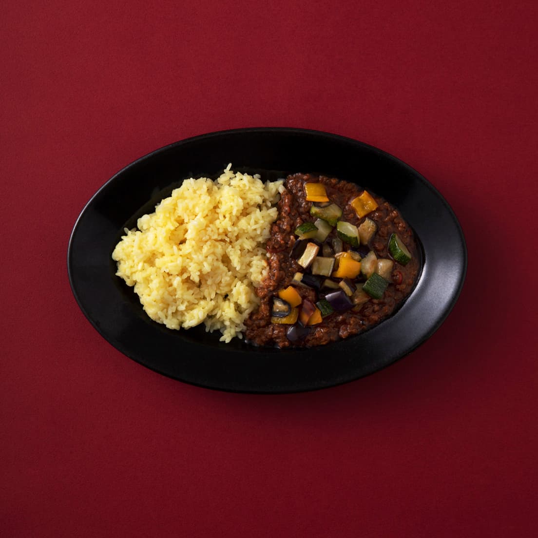 キーマやドライカレーなどぽってり系が好きなら、底が広めでフラットなプレートタイプのカレー皿を。〈郡司製陶所〉のオーバル皿は、黒いリムが額縁のような役割を果たすのが特徴。具だくさんカレー×サフランライスもモダンにまとまる。W27×D18×H3cm 4,950円。●うつわ楓 TEL 03 3402 8110。