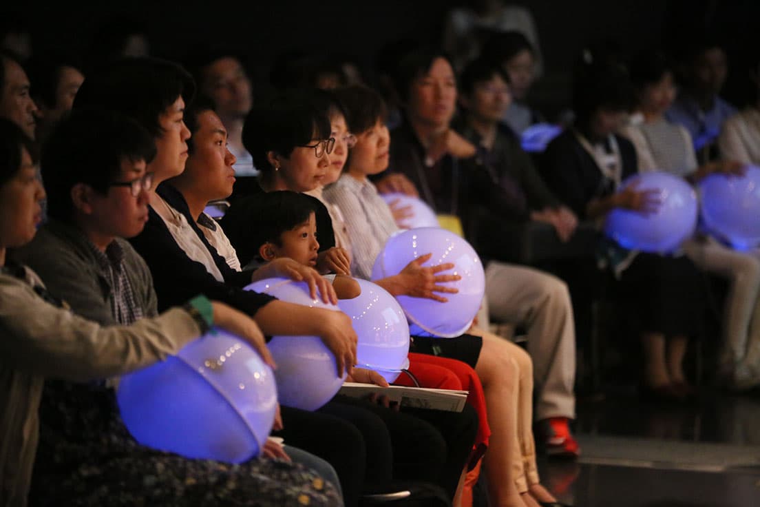 Vol.1「耳で聴かない音楽会」（2018年）会場の様子。色の変わる球体のデバイスから振動が伝わって音を”感じる”ことができる。　Ⓒ山口敦
