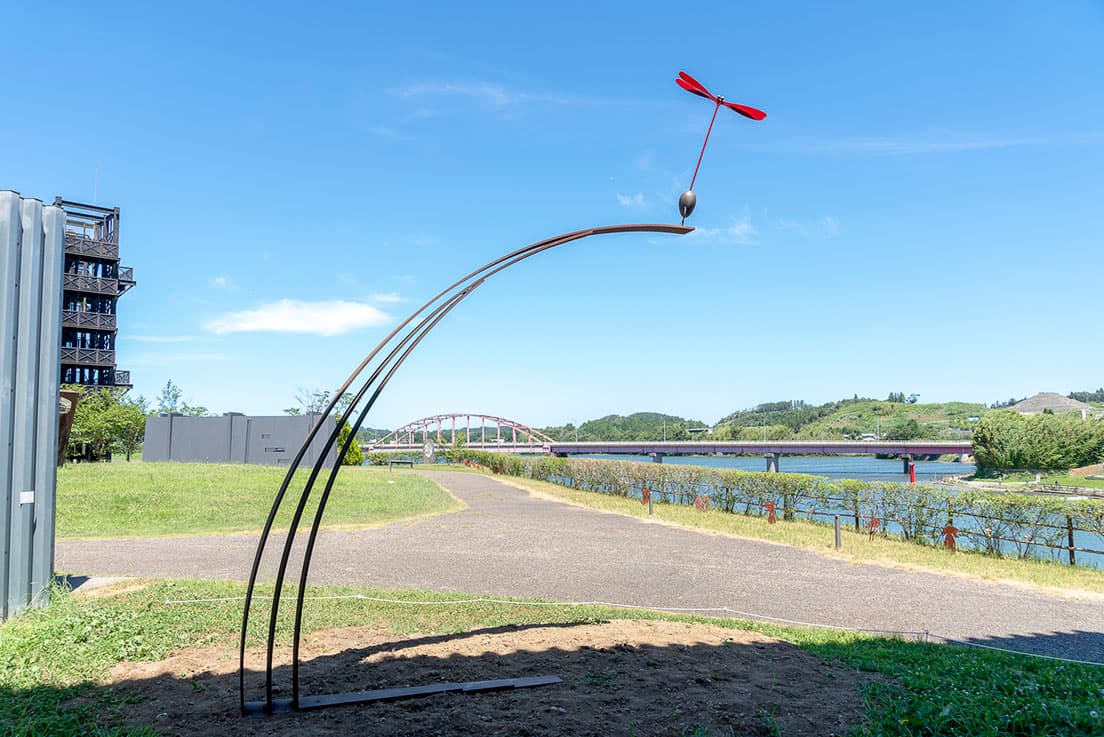 本展のために日立にある田中のアトリエから移設された《赤トンボ》。高滝湖畔に建つ〈市原湖畔美術館〉ののどかな風景に、赤トンボのオブジェが馴染む。田中による“赤トンボ”を使った作品といえば、2000年の『大地の芸術祭 越後妻有アートトリエンナーレ』で公開された作品《〇△□の塔と赤とんぼ》がよく知られている。