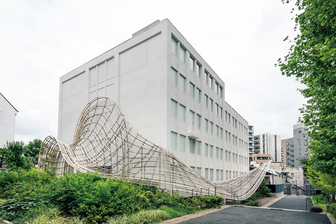 真っ白い箱型の建物に木製の庇が絡みつく外観。
