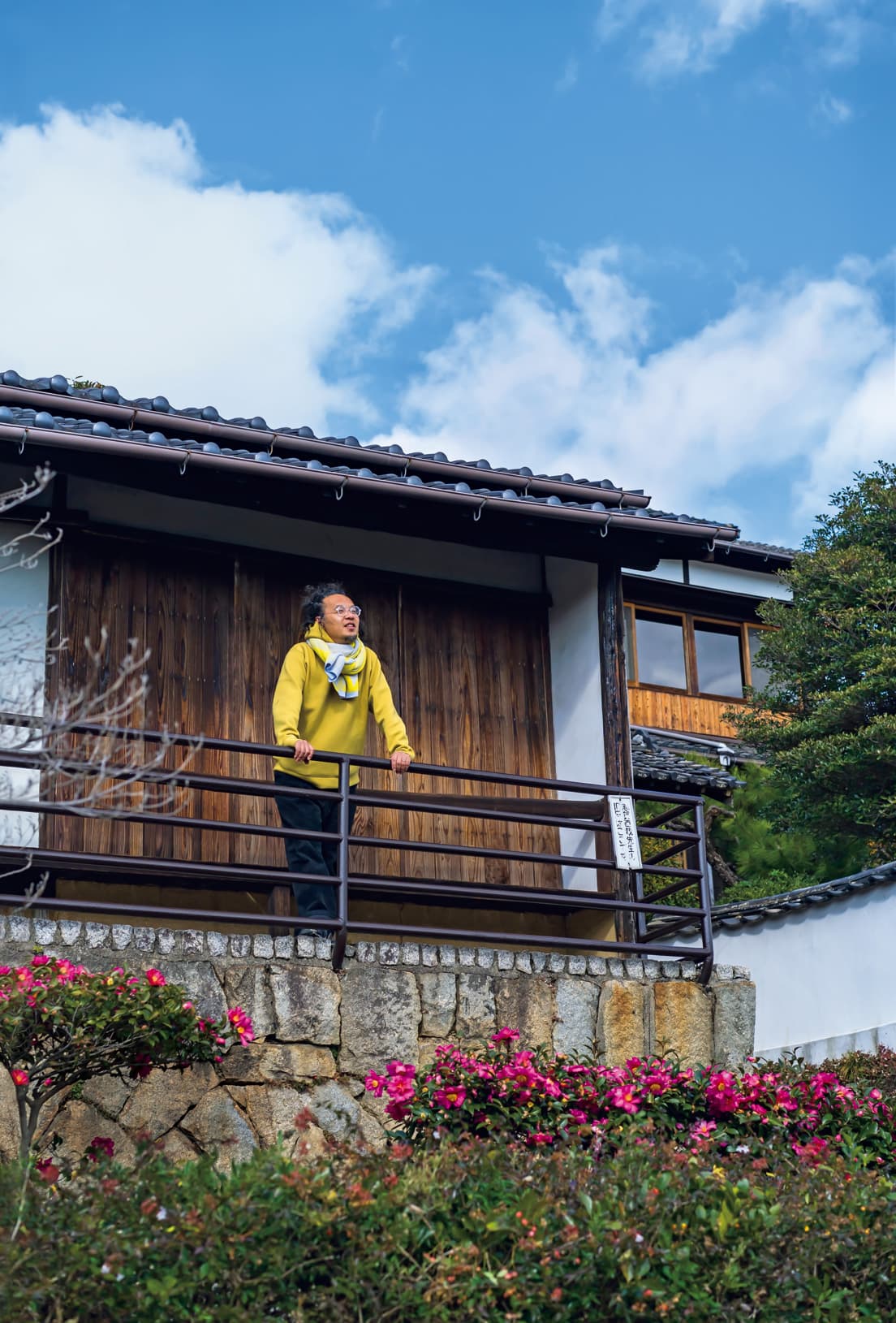 志賀直哉の旧居が含まれる3軒長屋の隅で尾道の街を眺める長坂常さん。奥の民家が計画拠点。志賀直哉が『暗夜行路』を構想したこの場所で、長坂さんも何か考えている模様。 photo_Yuna Yagi
