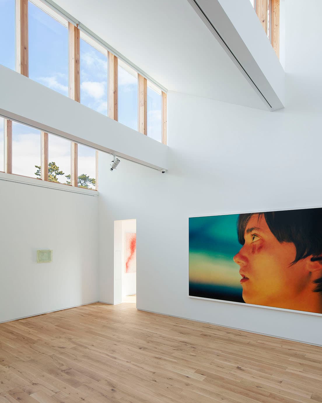 北側のハイサイドからの採光を活かした3階の大展示室。左側の壁に宮永愛子の《life》。正面はライアン・マッギンレーの《Taylor (Black &amp; Blue)》。右側に久松知子の作品も見える。 