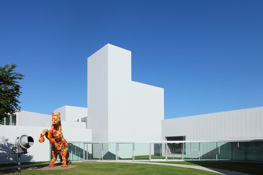 西沢良衛の設計による〈⼗和⽥市現代美術館〉外観。広場には、チェ・ジョンファの彫刻作品《フラワー・ホース》をはじめ多数のアートが展示されている。