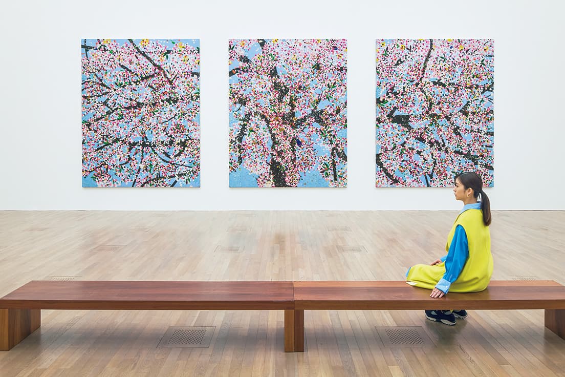 三幅対を思わせる三連画《生命の桜》を眺める長濱ねる。ハーストは東京で桜の季節に展覧会を催すことを快諾したという。日本特有の桜にまつわる死生観は彼の絵からも感じとれる。